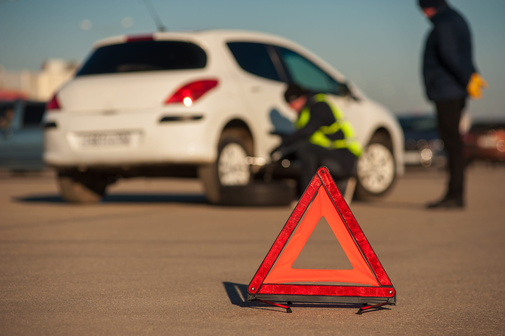 Használt gumiabroncs miatti lerobbanás után autószerelő cseréli a kereket az út szélén